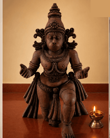 An antique carved deity lit by a brass oil lamp